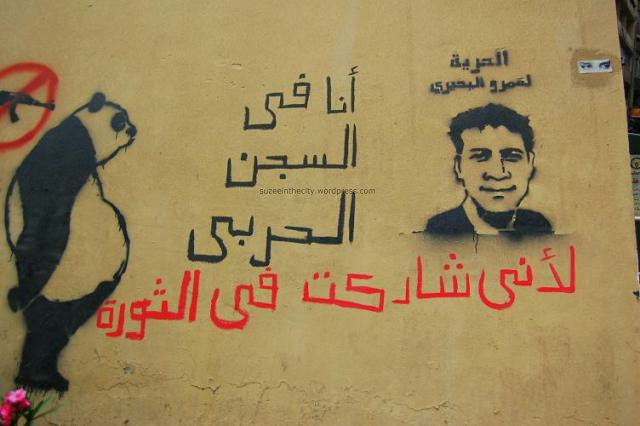 On the wall of a public bathroom on Abdel Salam Aref across from El Horreya, Sad Panda sits next to a graffiti stencil by Xist of Amr Beheiry, imprisoned Tahrir protester